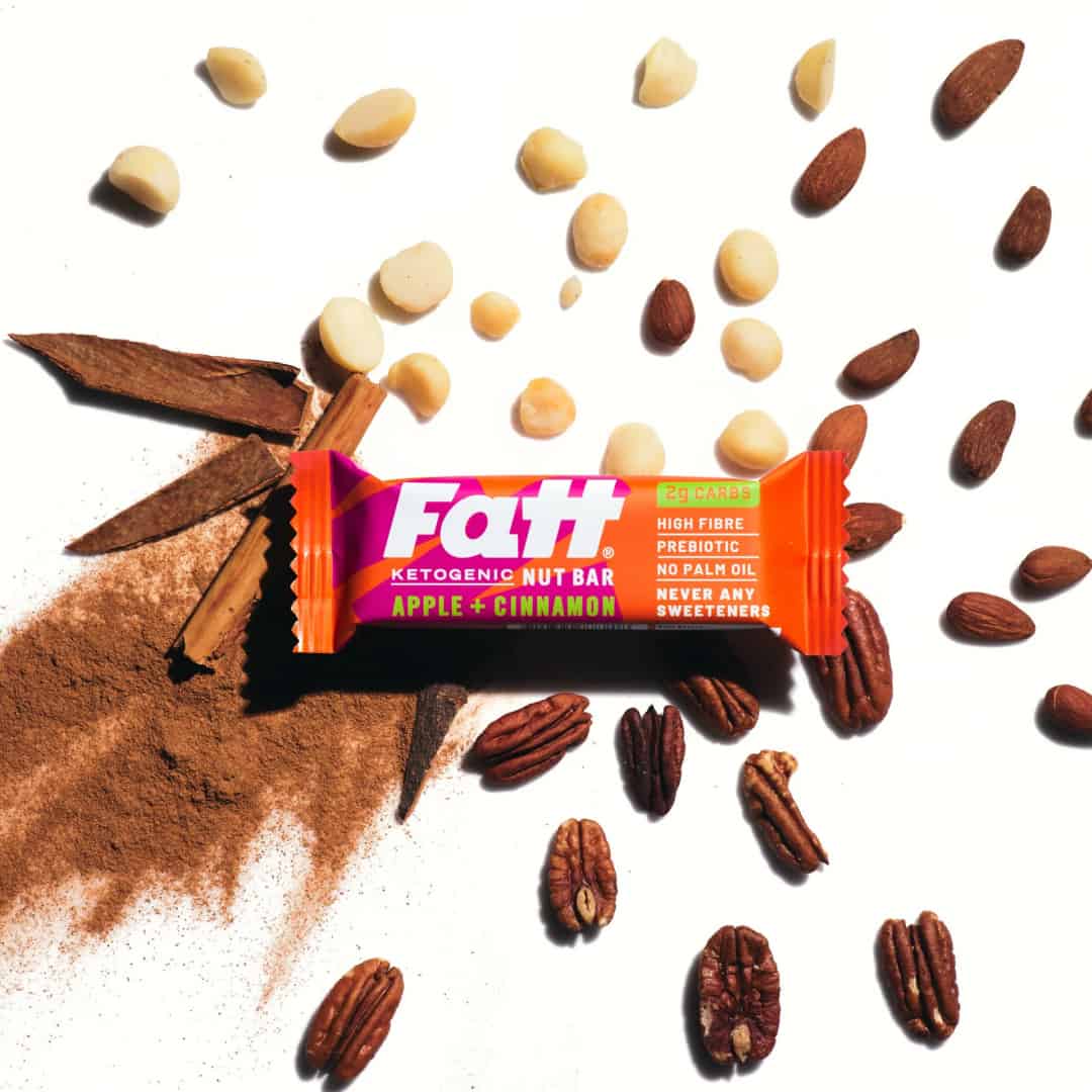 Fatt - Apple + Cinnamon 2 Fatt - Apple + Cinnamon bar on a white background with cinnamon, apple and almonds spread out behind it
