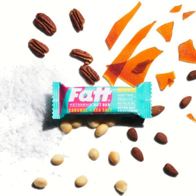Fatt - Caramel + Sea Salt bar on a white background, with caramel, almonds and flour spread out behind it.