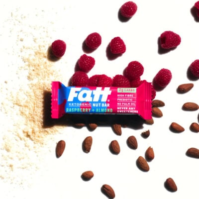 Fatt - Raspberry + Almond bar on a white background, with raspberry, almonds and flour spread out behind it.