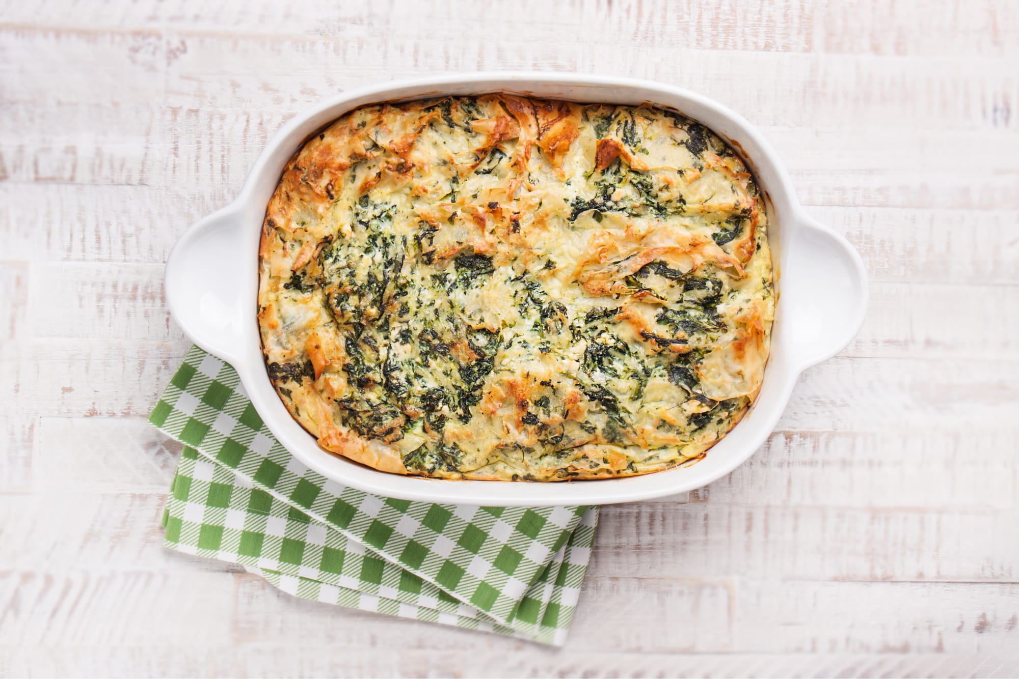 low carb chicken broccoli casserole seen from above, on a table with a green and white checkered tea towel