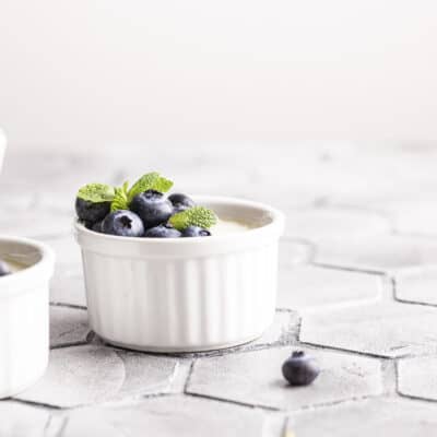 Low carb panna cotta in a white bowl with blueberries and a mint leaf on top
