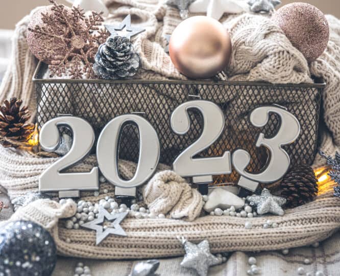 a basket of blankets and baubles with silver candles in front spelling out 2023